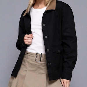 May include: A black jacket with a brown collar, featuring a button-up front and two front pockets. The jacket is paired with a white top and a khaki-colored skirt with a silver buckle.