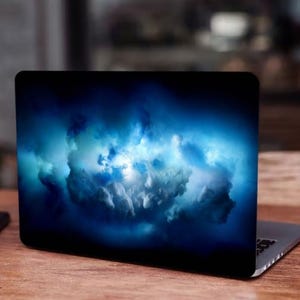 May include: A laptop computer with a dark blue and white abstract cloud design on the screen.