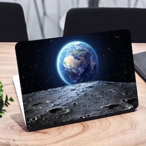May include: A laptop computer with a black and gray design featuring a close-up image of Earth rising over a moon-like surface.