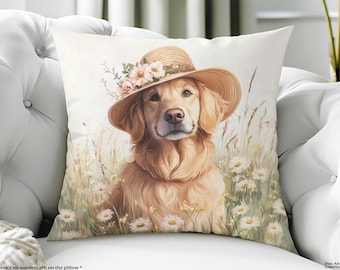 May include: A square throw pillow featuring a golden retriever wearing a straw hat adorned with pink and white flowers. The dog is depicted sitting in a field of white daisies and tall grass, rendered in a soft, light-toned artistic style.