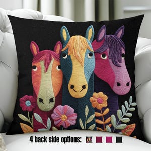 Puede incluir: Un cojín decorativo con fondo negro presenta un diseño bordado de tres cabezas de caballo coloridas. Los caballos son en tonos naranja, azul y rosa, con detalles florales. El texto "4 back side options:" está en la parte inferior.