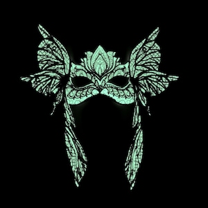 May include: A green masquerade mask with intricate butterfly wings and a floral design. The mask is made of a lightweight material and is perfect for a costume party or a masquerade ball.
