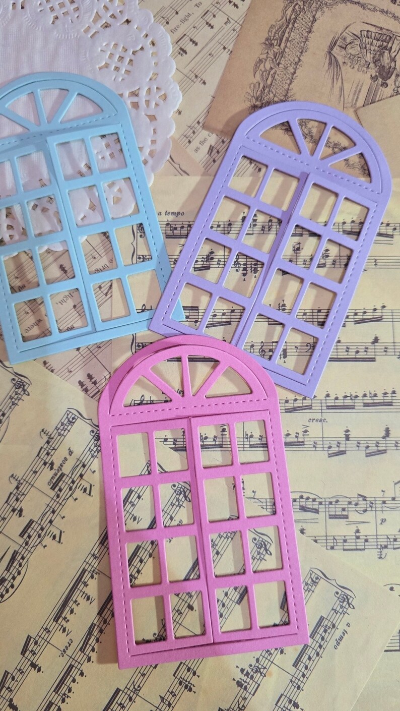 Puede incluir: Tres formas de marco de ventana troqueladas en azul, morado y rosa. Cada marco tiene una parte superior redondeada y una cuadr&iacute;cula de cuadrados. Los marcos est&aacute;n sobre un fondo de partituras musicales.