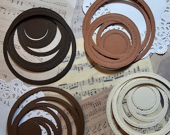 Puede incluir: Cuatro juegos de círculos concéntricos en marrón, beige y blanco. Cada juego tiene cinco círculos de diferentes tamaños. Los círculos están hechos de papel y tienen un borde cosido.