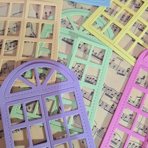 Puede incluir: Surtido de troqueles de marco de ventana de colores con borde cosido. Los troqueles est&aacute;n dispuestos en una hoja de papel de m&uacute;sica.