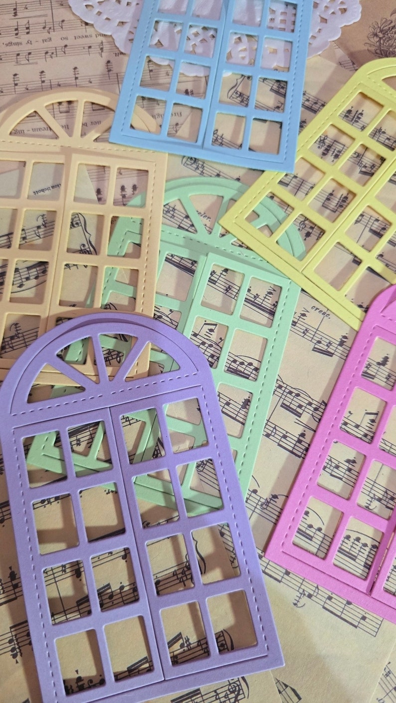 Puede incluir: Surtido de troqueles de marco de ventana de colores con borde cosido. Los troqueles est&aacute;n dispuestos en una hoja de papel de m&uacute;sica.