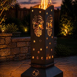 May include: A tall, black metal fire pit with a rectangular design. The sides feature cut-out skull and star designs, with flames visible at the top. The skull design incorporates the American flag. The fire pit is set on a stone patio.