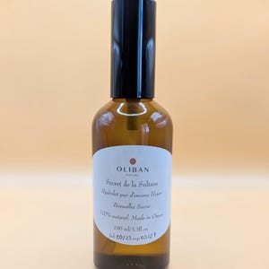 May include: A brown glass bottle with a black cap. The label reads "OLIBAN NATURE Secret de la Sultane Hydrolat pur d'encens Hojan Boswellia Sacra 100% naturel, Made in Oman 100 ml/3.3fl.oz". The expiration date is 09/21.