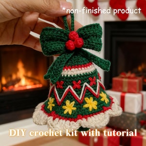 Könnte beinhalten: Handgefertigter Glockenornament aus grünem und weißem Häkelwerk, verziert mit roten Beeren und einer Schleife. Die Glocke hat rote und gelbe Blumenmuster und den Text "DIY crochet kit with tutorial".