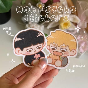 Könnte beinhalten: Zwei Aufkleber im Anime-Stil mit Charakteren aus "Mob Psycho 100". Ein Aufkleber zeigt einen Charakter mit schwarzen Haaren und einer Blume, der andere mit blonden Haaren und einem Burger. Die Aufkleber tragen den Text "MOB PSYCHO Stickers".