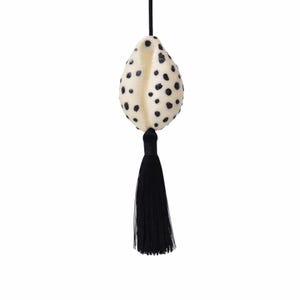 May include: Cream-colored, teardrop-shaped ornament with black polka dots and a black tassel. The ornament is suspended by a thin black string, creating a simple, elegant design. This decorative piece could be used as a Christmas ornament or a unique home decor accent.