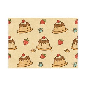 May include: A rectangular fabric featuring a repeating pattern of tan custard puddings topped with brown syrup, white cream, and red strawberries, interspersed with small red strawberries and light blue paw prints on a light beige background.