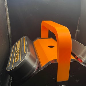 Pode incluir: Uma caixa de ferramentas preta e laranja com uma al&ccedil;a. A caixa de ferramentas tem as palavras "Powered by Ford" impressas no lado.