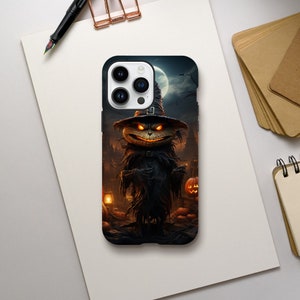 Puede incluir: Funda de teléfono negra con una ilustración de Halloween. El diseño representa una criatura espeluznante con ojos naranja brillantes y una sonrisa siniestra, con un sombrero de bruja, sobre un fondo de un pueblo embrujado.