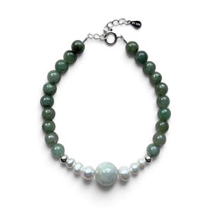 May include: A beaded bracelet featuring round green jade-like stones, white freshwater pearls, and a central large pale green bead. The piece includes a silver-toned metal clasp and an extension chain with a small tag marked 925.