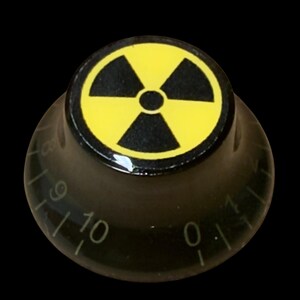 May include: A black cylindrical control knob featuring a yellow circular top with a black radiation hazard symbol. The side of the knob is marked with white numbers ranging from zero to ten, indicating a graduated scale for precise adjustment.