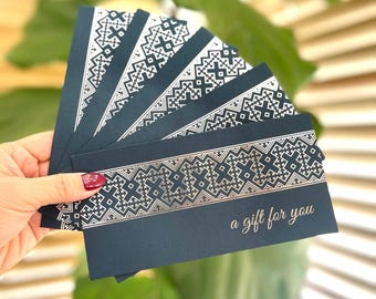 May include: A stack of dark blue gift cards with a silver and white geometric pattern and the text "a gift for you".