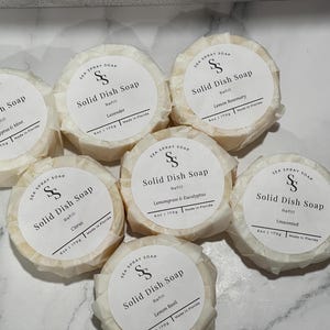May include: Seven round bars of Sea Spray Soap solid dish soap refills, each wrapped in white paper with a circular label. The labels feature the text 'Solid Dish Soap', 'Refill', '6oz | 170g', 'Made in Florida', and specific scents including Eucalyptus & Mint, Lavender, Lemon Rosemary, Citrus, Lemongrass & Eucalyptus, Unscented, and Lemon Basil.