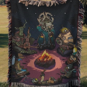 May include: A woven throw blanket featuring a dark, starry night scene with five distinct characters gathered around a central campfire. The characters include a tree-like figure, a robotic entity, and others playing various musical instruments.