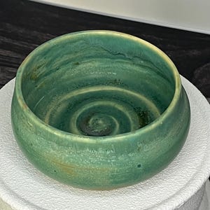 丸みを帯びた有機的なフォルムの、手作りの小さな陶器のボウル。縁がわずかに不規則な形状をしており、ろくろで成形したような風合いを醸し出している。