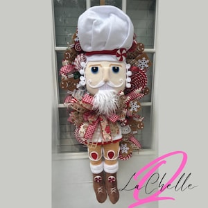 May include: A gingerbread man nutcracker Christmas wreath with a white chef's hat, red and white candy canes, and a brown gingerbread house.