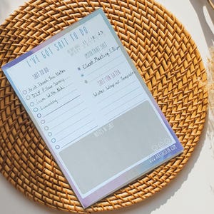 May include: A light blue and gray to-do list notepad with the text "I've got shit to do" at the top. The notepad has a checklist with the text "Shit to do" and "Shit for later" and a section for notes.