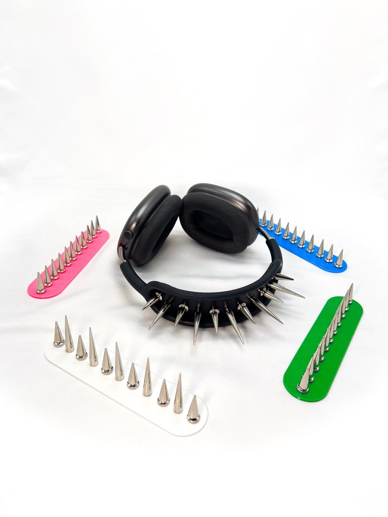 May include: Black headphones with a studded collar and several colored spike strips. The collar is black with silver spikes. The spike strips are pink, blue, green, and white.