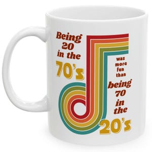 May include: White ceramic mug with a rainbow design and the text "Being 20 in the 70's was more fun than being 70 in the 20's".
