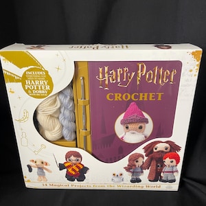 May include: A Harry Potter crochet kit with a book, yarn, and crochet hooks. The box features the title "Harry Potter Crochet" and includes images of crocheted characters like Dobby, Harry, and Ron. The kit includes everything needed to make Harry Potter and Dobby with his sock.