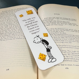 May include: White bookmark with the text "The only way to protect yourself from the Cheese Touch is to cross your fingers." Features a cartoon illustration of a character and cheese graphics.
