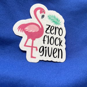 Puede incluir: Una pegatina de flamenco rosa con una hoja de palmera verde y el texto "zero flock given".