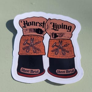 May include: A sticker featuring two work gloves with the words "Honest Living" in a vintage font. The gloves are orange and black, with tools and the words "Sheet Metal" on the bottom.