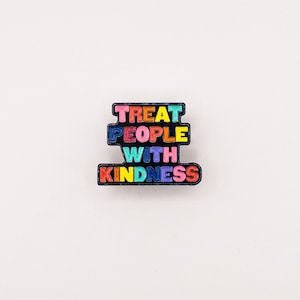 May include: A black enamel pin with the words "Treat People With Kindness" in rainbow colours.