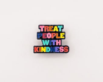 May include: A black enamel pin with the words "Treat People With Kindness" in rainbow colors.