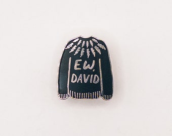 May include: Black enamel pin shaped like a sweater with a silver lightning bolt pattern and the text "EW DAVID" in silver lettering.