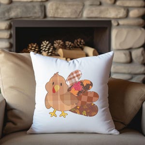 May include: White square throw pillow featuring a cartoon turkey design. The turkey has a plaid body, a red wattle, and a yellow beak and feet. The tail feathers are a mix of plaid and fall-themed patterns.