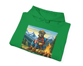 May include: A green hoodie featuring a cartoon image of a dog sitting by a campfire in the mountains. The dog is wearing a plaid shirt and holding a mug. The text "Camp Dog" is printed below the image.
