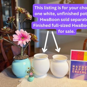 May include: Two white, unfinished pots are displayed on a table, with a small turquoise pot and a larger blue pot with a pink flower arrangement. The text on the image says, "This listing is for your choice of one white, unfinished pot."