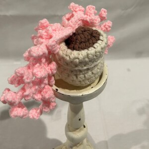 Planta en maceta de ganchillo con flor rosa