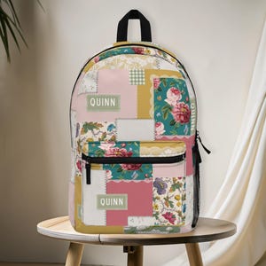 May include: A patchwork backpack with a variety of floral and geometric patterns in pink, teal, yellow, and white. The backpack has a black zipper, a front pocket, and the name "Quinn" printed on it.