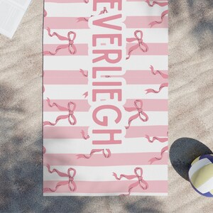 Custom name coquette bow beach towel in a stylish design, perfect for girls, teens, and kids. A personalized pool towel ideal for spring break, vacations, and bachelorette gifts. This trendy custom color towel makes a great gift idea for any occasion.
