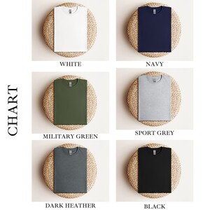 Puede incluir: Una tabla de colores para camisetas Gildan 64000. La tabla muestra seis colores diferentes: blanco, azul marino, verde militar, gris deportivo, gris oscuro jaspeado y negro.