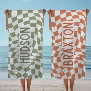 May include: Two beach towels with a checkered pattern in green and white and orange and white. The towels have the names "HUDSON" and "BRAXTON" printed on them.