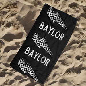 May include: Black beach towel with a white checkered lightning bolt design and the word "BAYLOR" repeated three times.