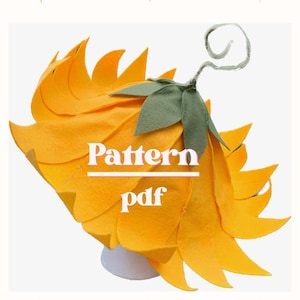 May include: A felt sunflower costume with the text "Pattern pdf". The costume is predominantly bright yellow with green leaves and a curled stem. The petals are layered and pointed, creating a three-dimensional effect.