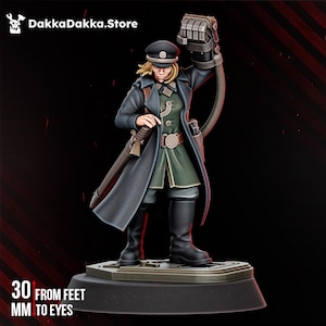 May include: A miniature figurine of a military officer wearing a dark coat, green tunic, and peaked cap, with a raised mechanical power fist. The figure stands on a base with text indicating a scale of 30 mm from feet to eyes and DakkaDakka.Store.