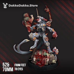 May include: A detailed miniature figure of a monstrous creature with a horn, holding a severed head and weapon. The figure is primarily gray with orange and red accents. The text "DakkaDakka.Store" is at the top. The figure is 52mm from feet and 70mm to eyes.