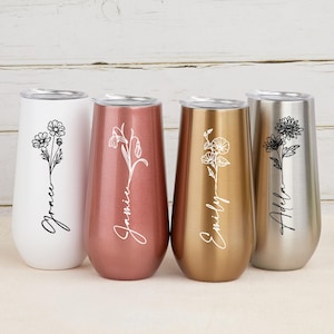 Peut inclure: Quatre flûtes à champagne sans pied blanches, or rose, dorées et argentées. Chaque gobelet présente un motif floral et un nom en écriture cursive. Les flûtes sont en acier inoxydable et ont un couvercle.