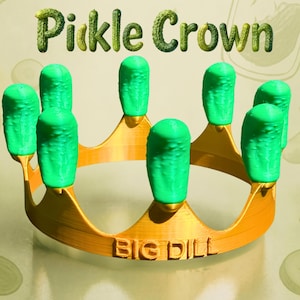 May include: A gold-colored crown featuring several bright green, textured pickle-shaped toppers attached to the points. The front of the crown band is embossed with the text BIG DILL, while the background displays the text Pickle Crown.