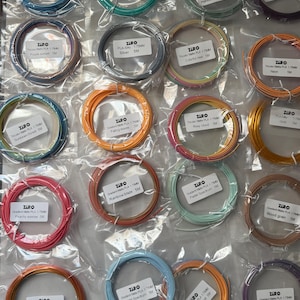 May include: A collection of ZIRO brand PLA filament spools in various colors, including blue, green, orange, and pink. Each spool is labeled with its color name and specifications. The spools are packaged in clear plastic.